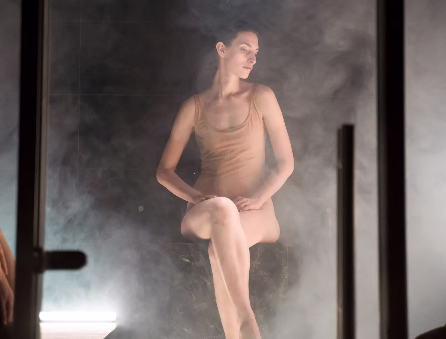 Mujer sentada en un baño de vapor de White Bahamas, envuelta en niebla cálida